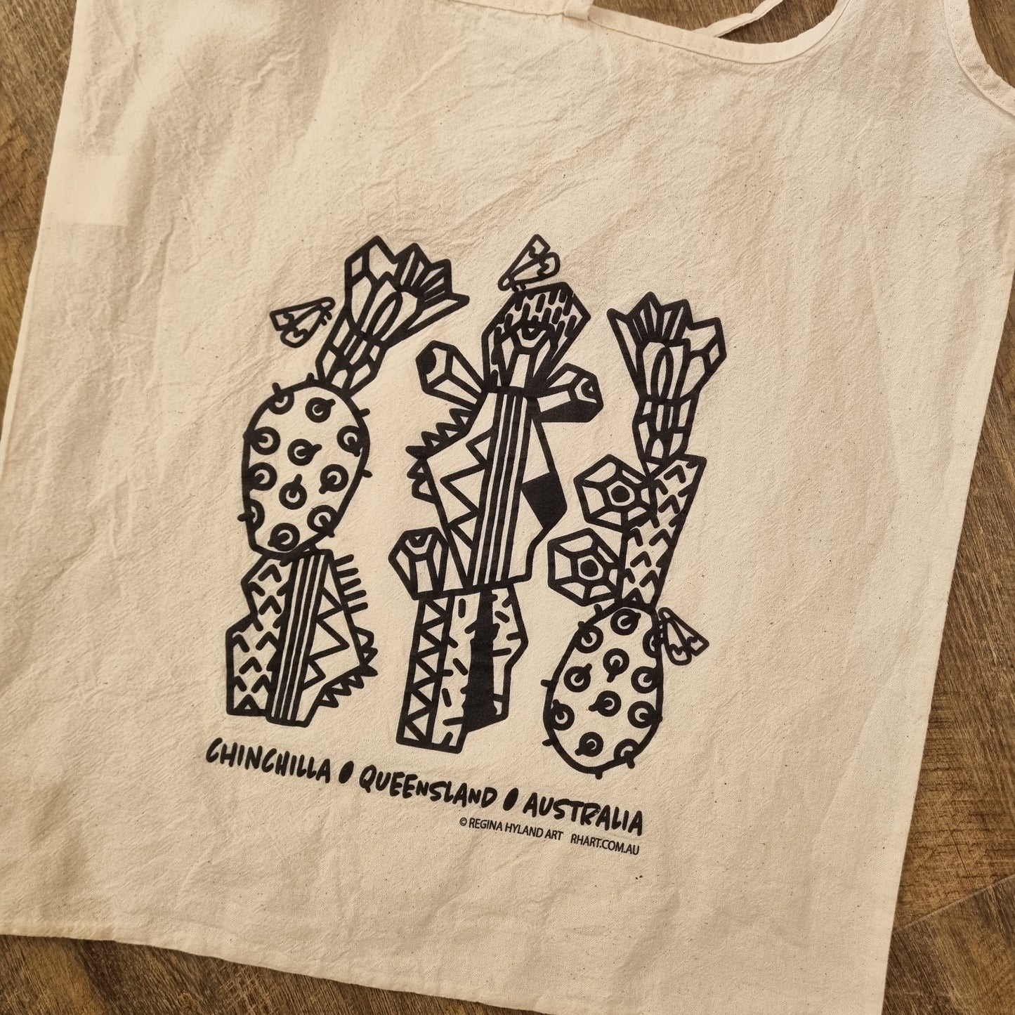 A natural calico tote bag with a black stylized cacto-blastis print. Inspired by Chinchilla, Queensland, Australia. The bag has two long handles and an eco-friendly design.