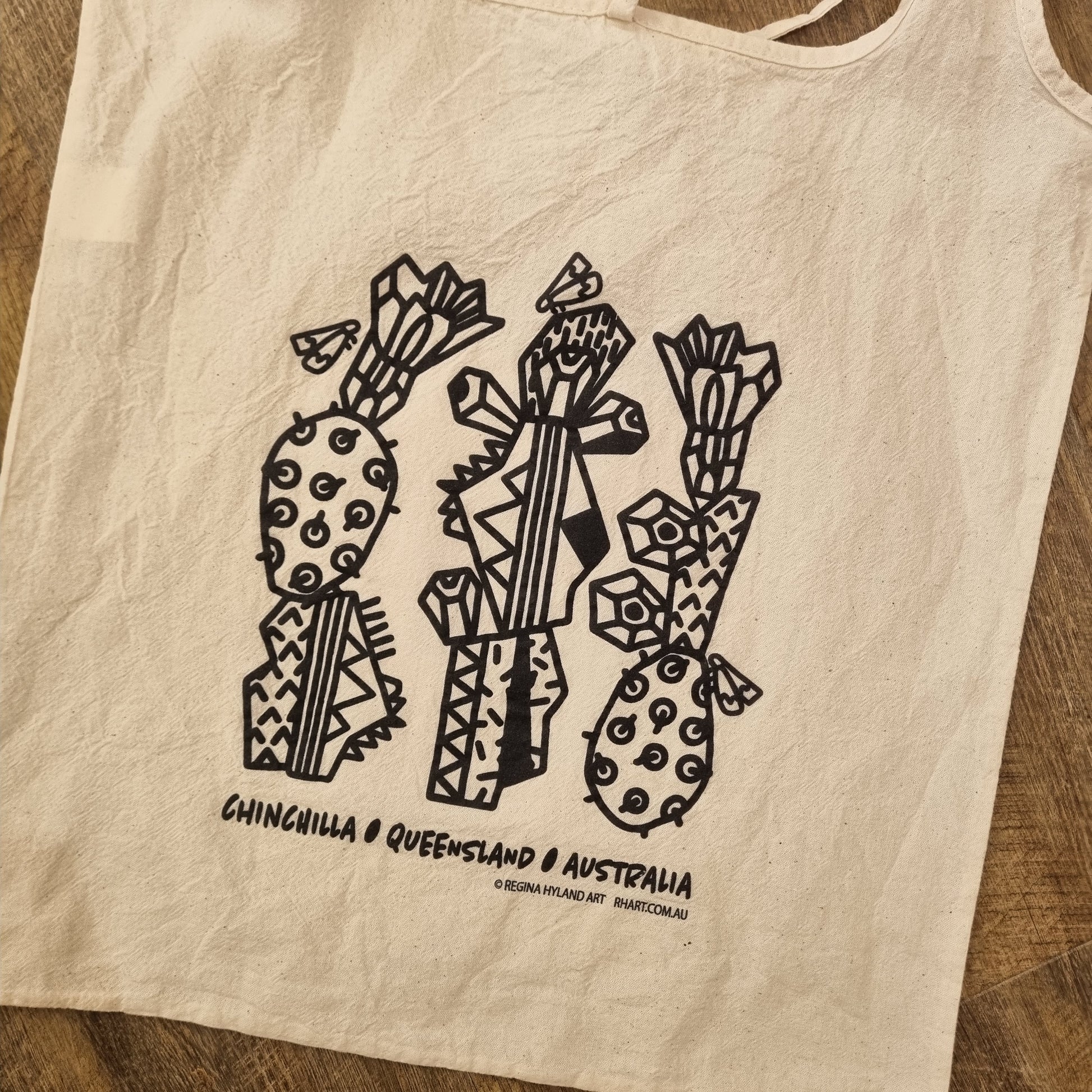 A natural calico tote bag with a black stylized cacto-blastis print. Inspired by Chinchilla, Queensland, Australia. The bag has two long handles and an eco-friendly design.