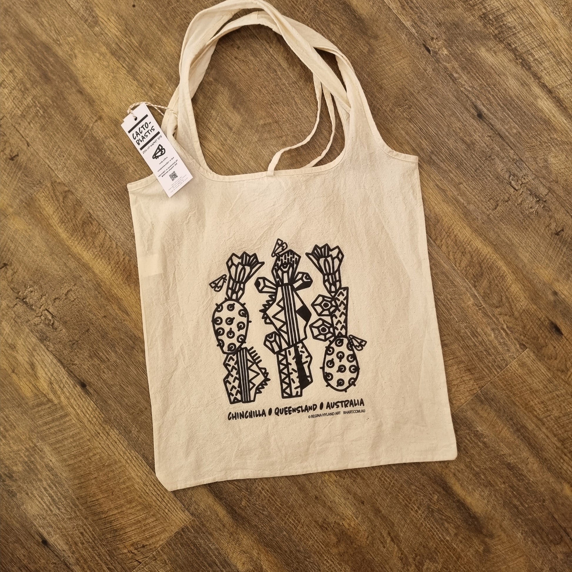 A natural calico tote bag with a black stylized cacto-blastis print. Inspired by Chinchilla, Queensland, Australia. The bag has two long handles and an eco-friendly design.